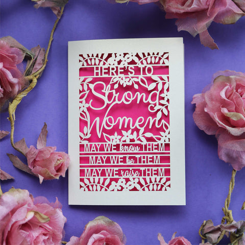 A laser cut card that says "Here's to Strong women. May we know them, may we be them, may we raise them."