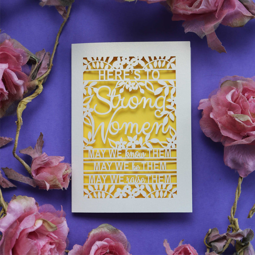 A laser cut Card  for her that says "Here's to Strong Women, may we know them, may we be them, may we raise them"