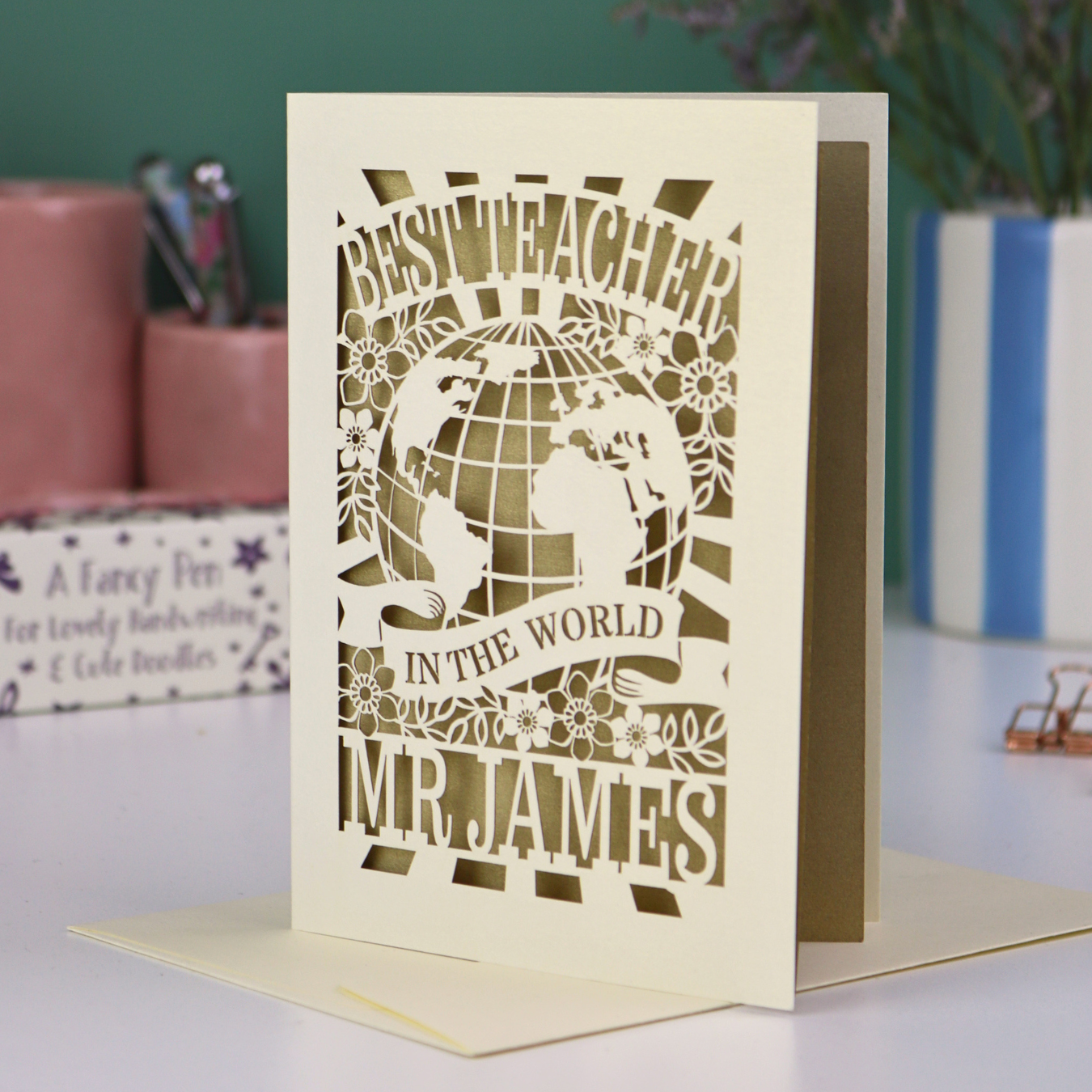 A laser cut cream thank you teacher card with globe design and the text Best Teacher in the World Mr James"
