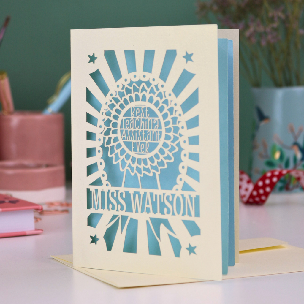 A laser cut unique thank you teaching assistant card with cut out rosette design and text "Best Teaching Assistant Ever" and personalised with the name "Miss Watson"