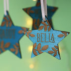 Personalised Christmas decorations, star shaped and pained teal with names engraved.