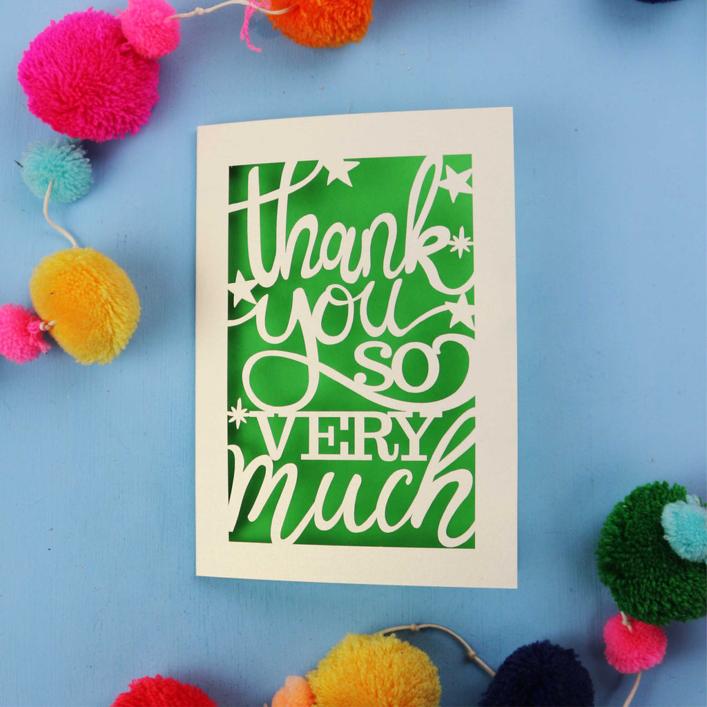 Laser cut thank you card with 'Thank you so very much' text on a blue background with colourful pom-poms.