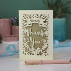 Personalised Laser-cut 'Thank you' card with decorative elements on a table with stationery items.