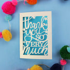 Cut out thank you card with 'Thank you so very much' text on a blue background with colourful pom-poms.