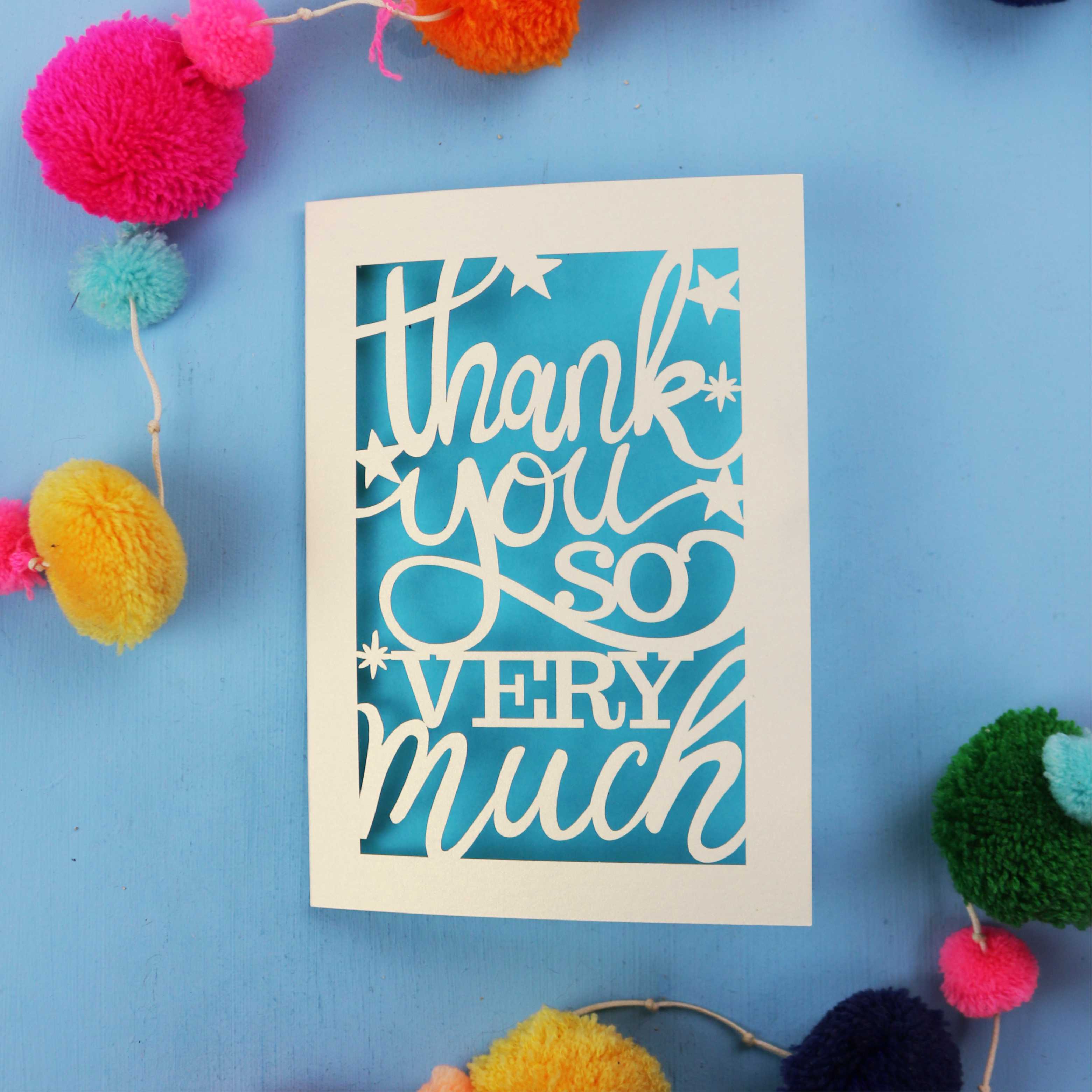 Cut out thank you card with 'Thank you so very much' text on a blue background with colourful pom-poms.