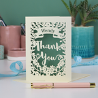 Personalised cut out 'Thank you' card with decorative elements on a table with stationery items.
