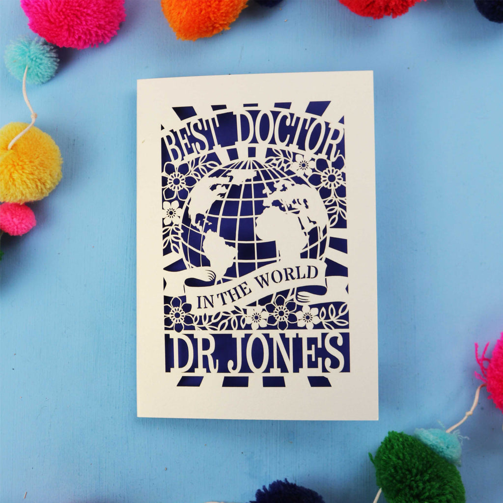 Personalised thank you Doctor card with 'Best Doctor in the World' text on a blue background with colourful pom-poms.
