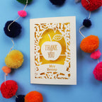 Personalised thank you teacher card with 'Thank You Mrs Benny' text surrounded by colourful pom-poms on a blue background