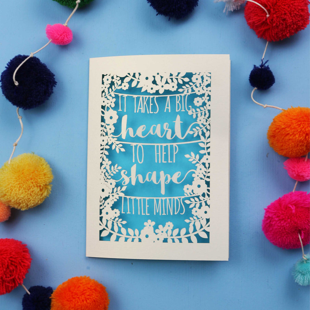 Thank you teacher card with motivational quote surrounded by colourful pom-poms on a blue background