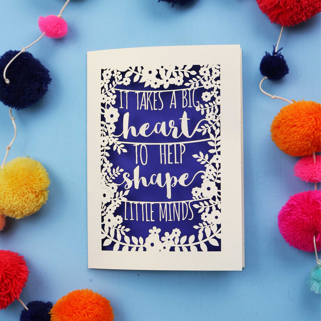 Cut out Thank you teacher card with motivational quote surrounded by colourful pom-poms on a blue background