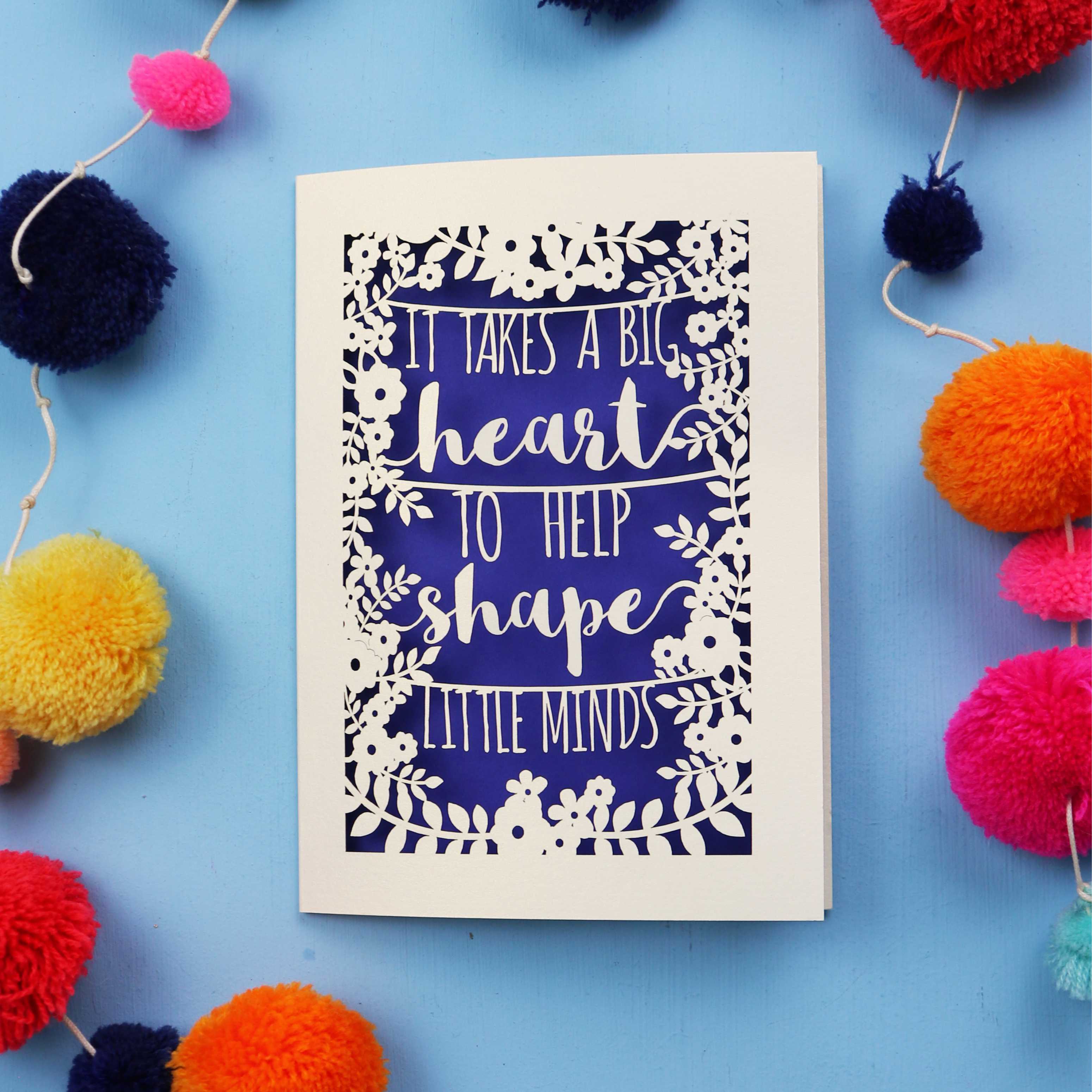 Cut out Thank you teacher card with motivational quote surrounded by colourful pom-poms on a blue background