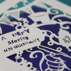 Decorative birthday card with intricate cut-out patterns and text.