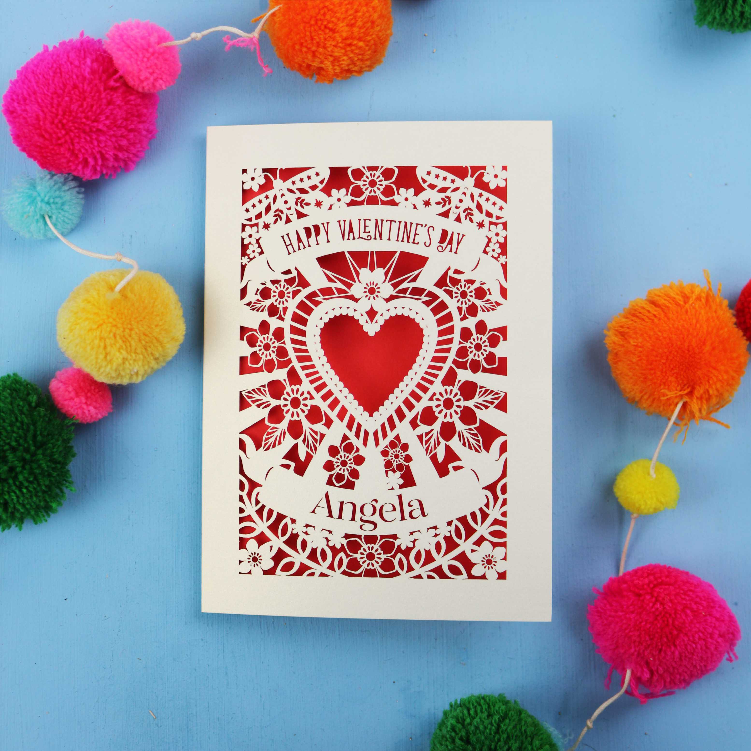Personalised Valentine's Day card with decorative heart design on a blue background with colourful pom-poms.