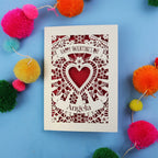 Valentine's Day card with decorative heart design on a blue background with colourful pom-poms.