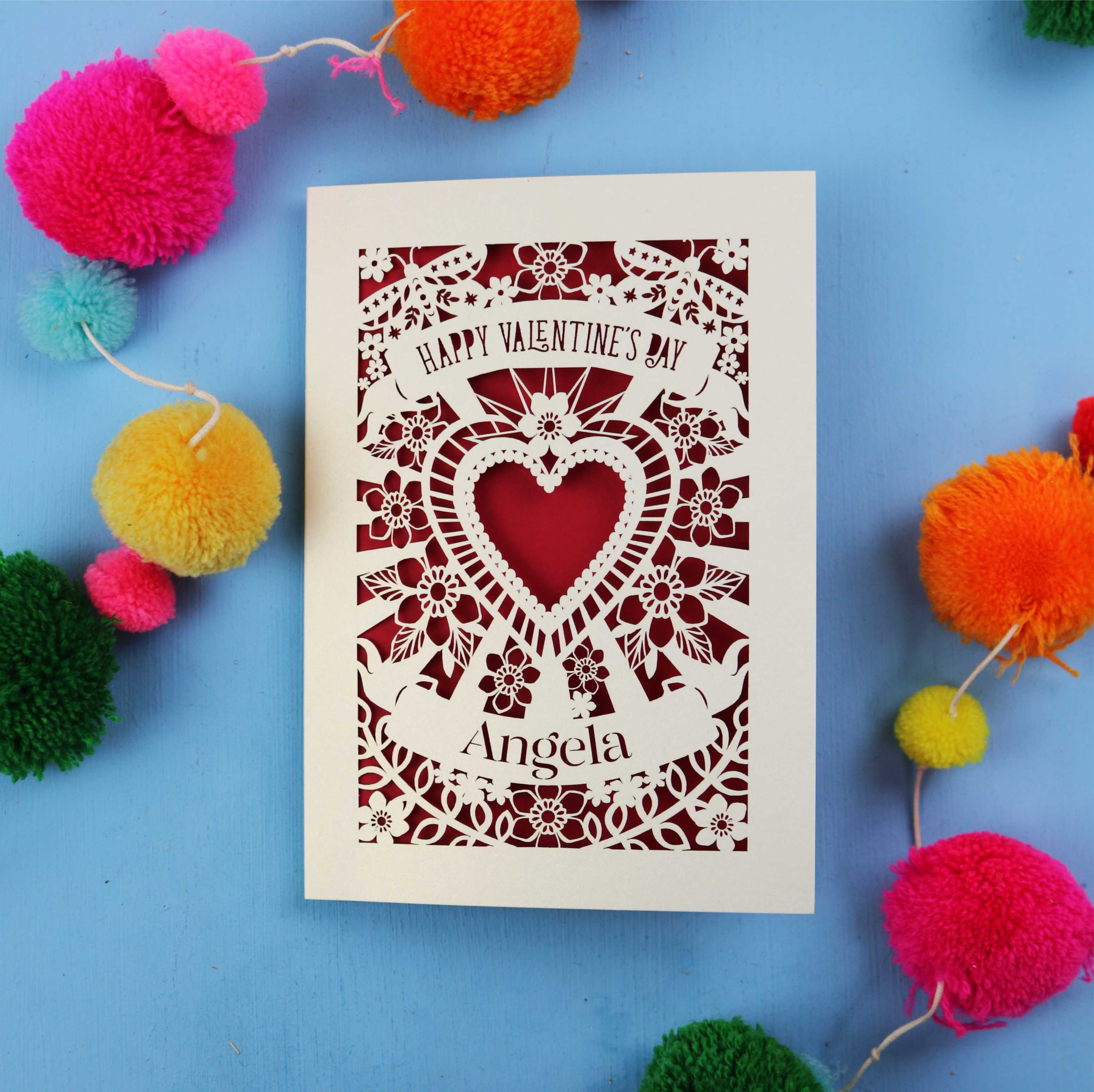 Valentine's Day card with decorative heart design on a blue background with colourful pom-poms.