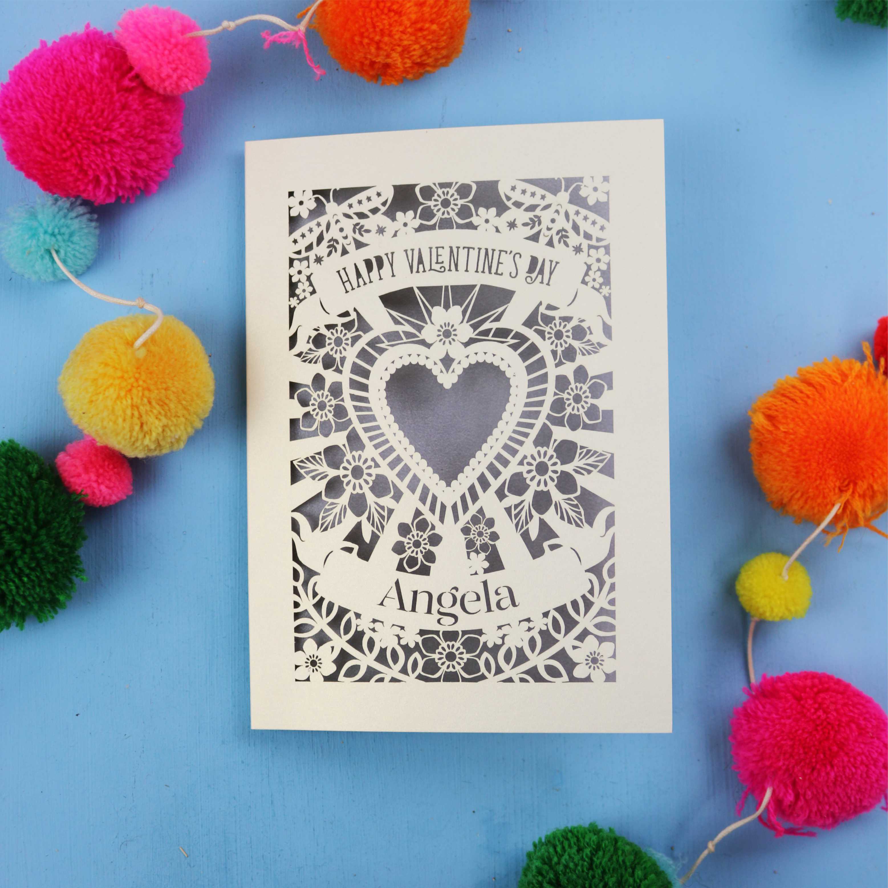 Luxury Valentine's Day card with decorative heart design on a blue background with colourful pom-poms.