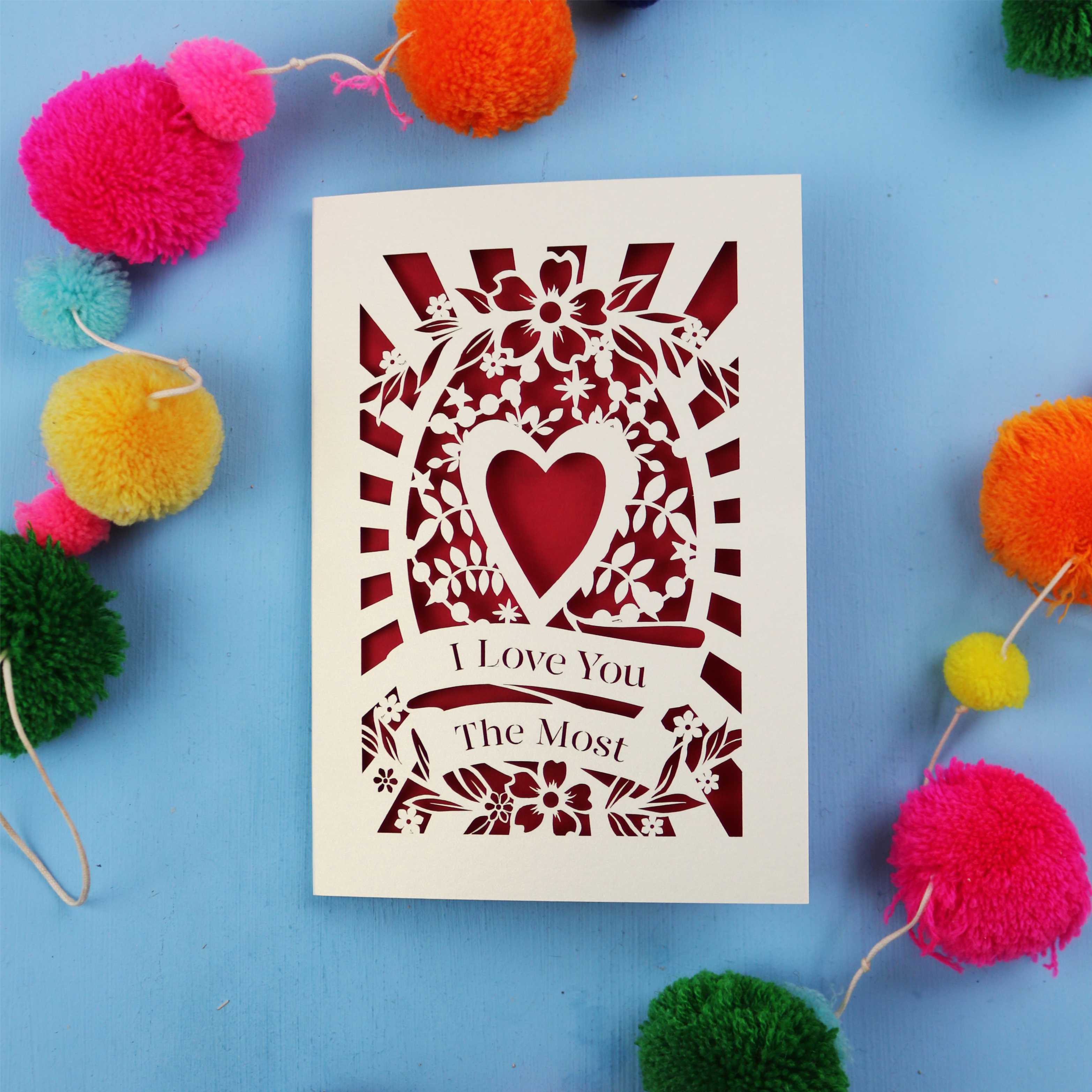 Valentines Card UK, with 'I Love You The Most' design on a blue background with colourful pom-poms.