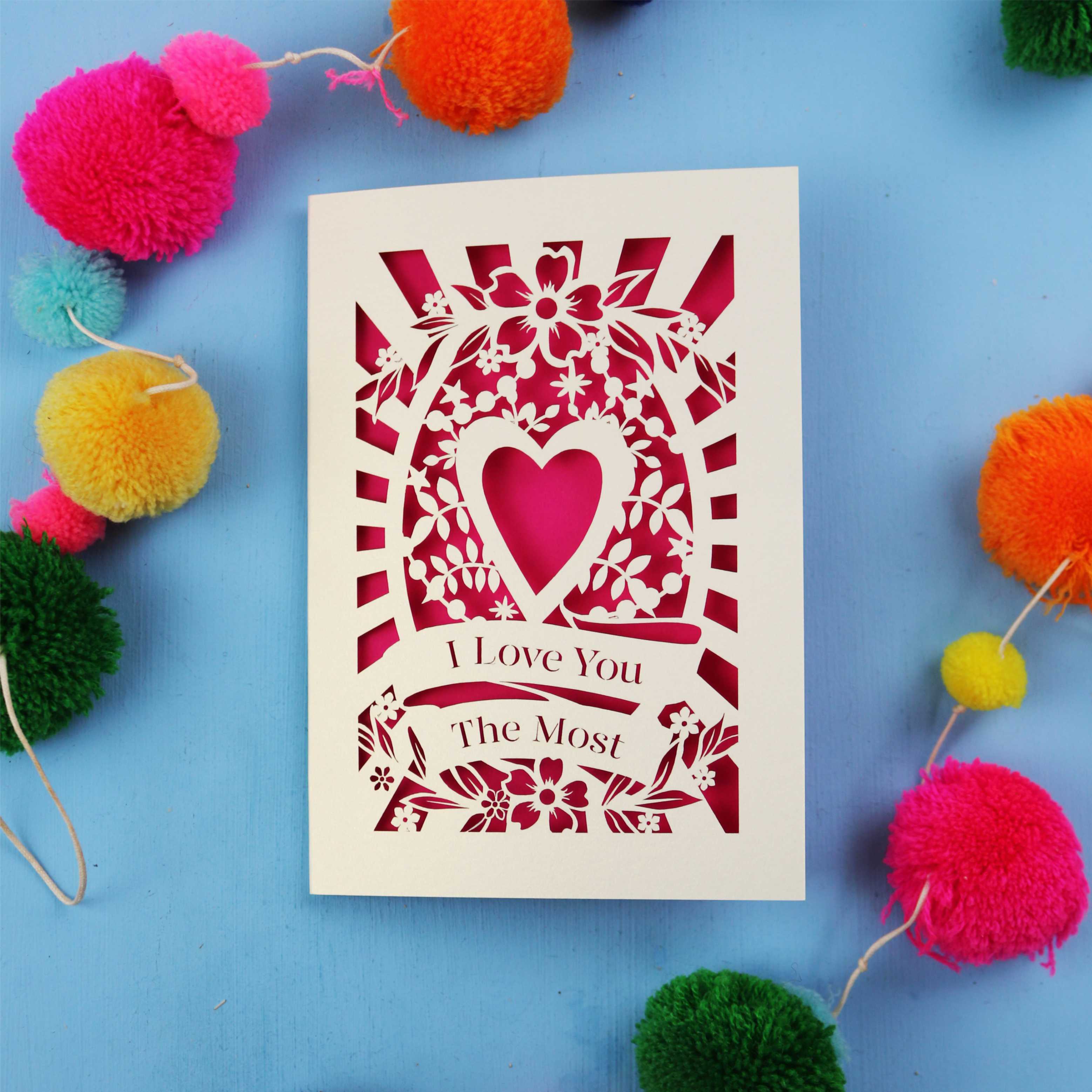 Valentines Card with 'I Love You The Most' design on a blue background with colourful pom-poms.