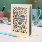 Personalized vow renewal card with decorative heart design on a table.