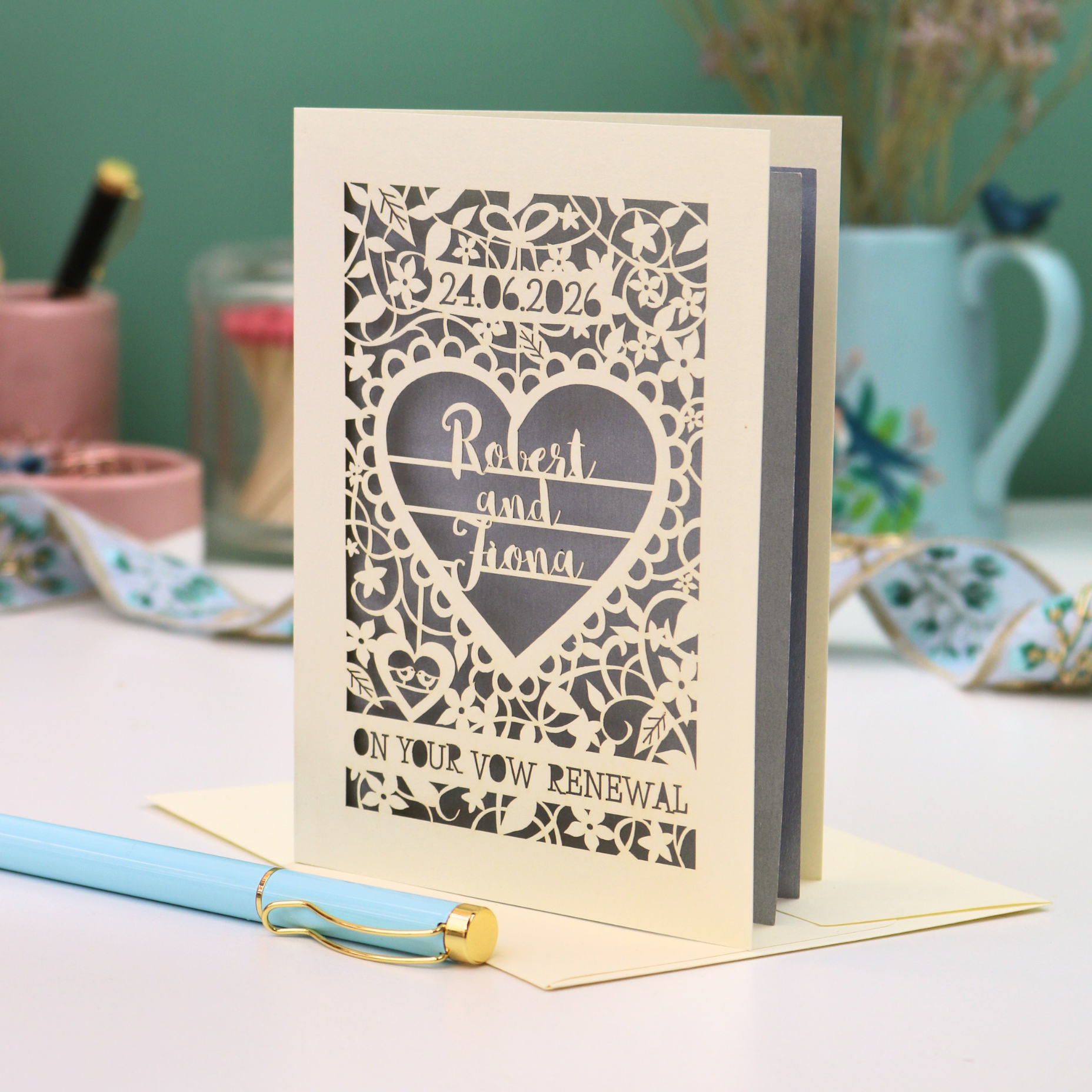 Personalized vow renewal card with decorative heart design on a table.