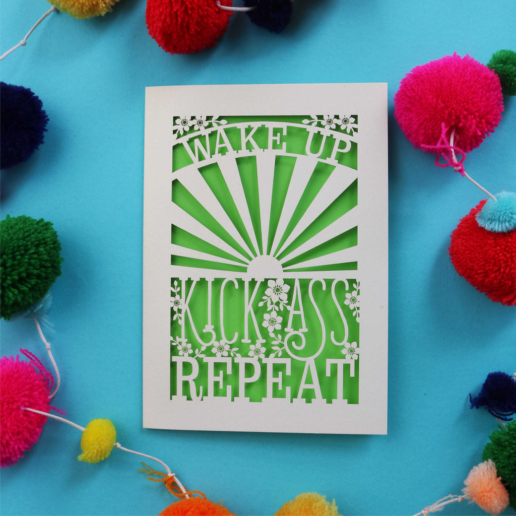A laser cut motivational greetings card that says "Wake up, Kick ass, repeat"