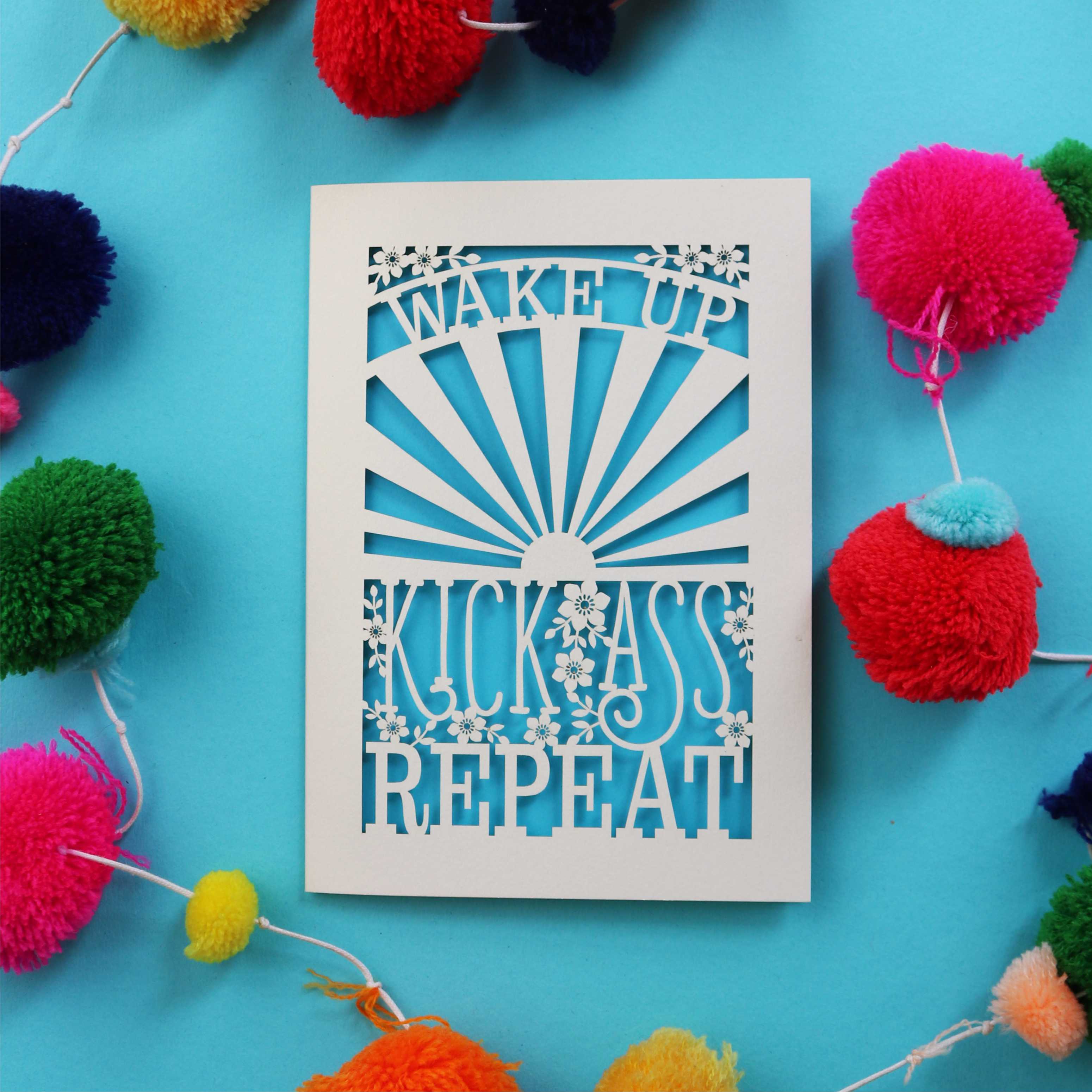 A laser cut good luck card that says "Wake up, Kick ass, repeat"