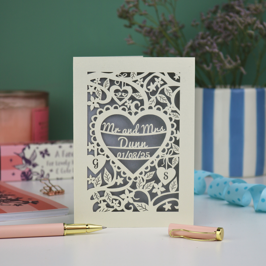 Personalized anniversary card with decorative heart design on a table with stationery items.