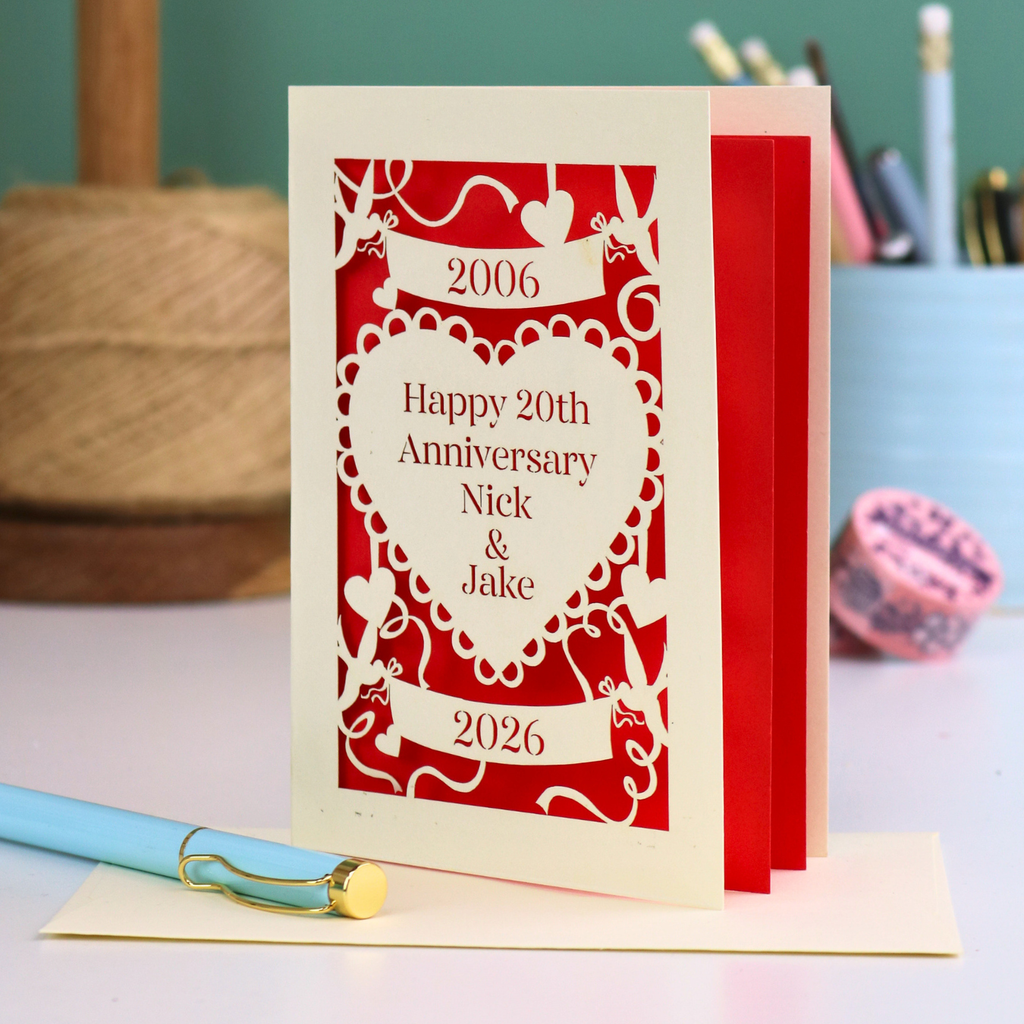 20th anniversary card with red and white design on a table with stationery items.