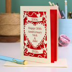 20th anniversary card with red and white design on a table with stationery items.