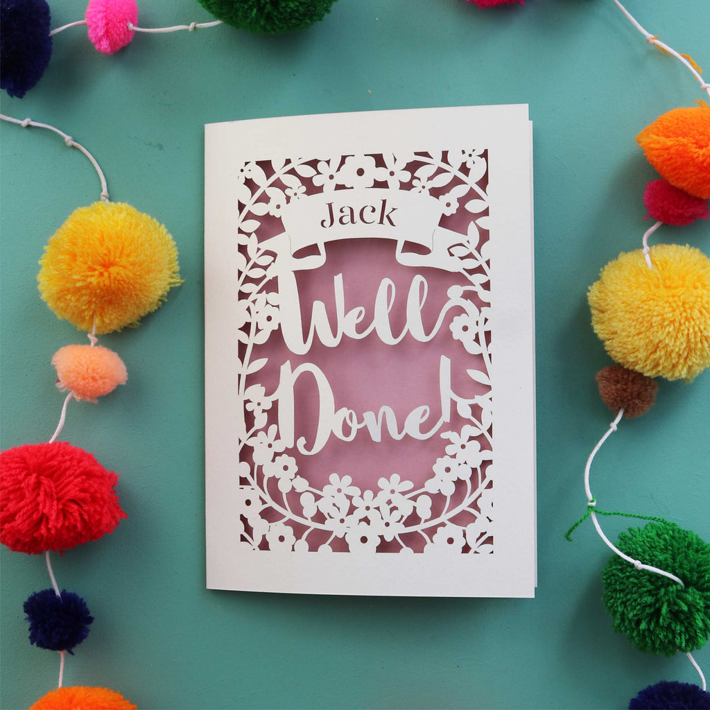 A personalised celebration card that says "Well Done" and has the recipient's name in a banner