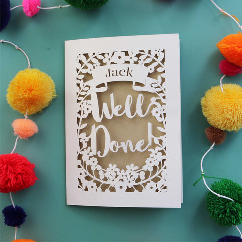 A laser cut congratulations card, personalised with a name. Card has the words "Well Done!" in a script font