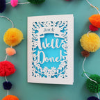 A personalised exam congratulations card that says "Well Done" and has the recipient's name in a banner