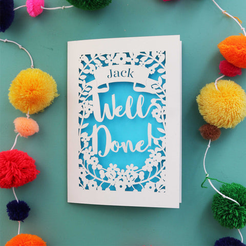 A personalised exam congratulations card that says "Well Done" and has the recipient's name in a banner - A5 / Peacock Blue