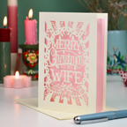 A laser cut wife Christmas card in cream and candy pink with decorative cut out text, 'Merry Christmas to my Wife'
