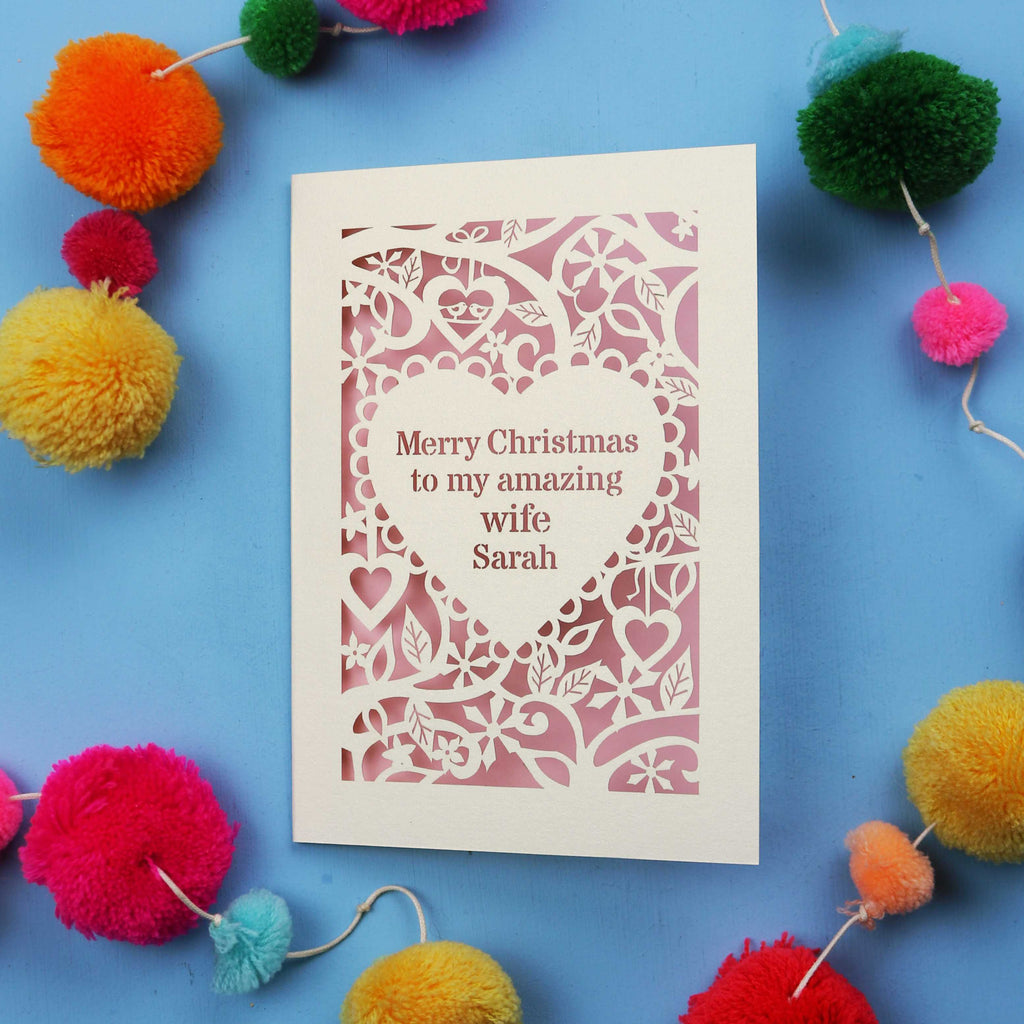 Christmas card with personalized message surrounded by colourful pom-poms on a blue background