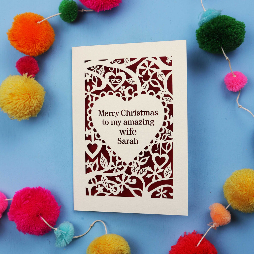 Christmas card with personalized message on a blue background with colourful pom-poms.