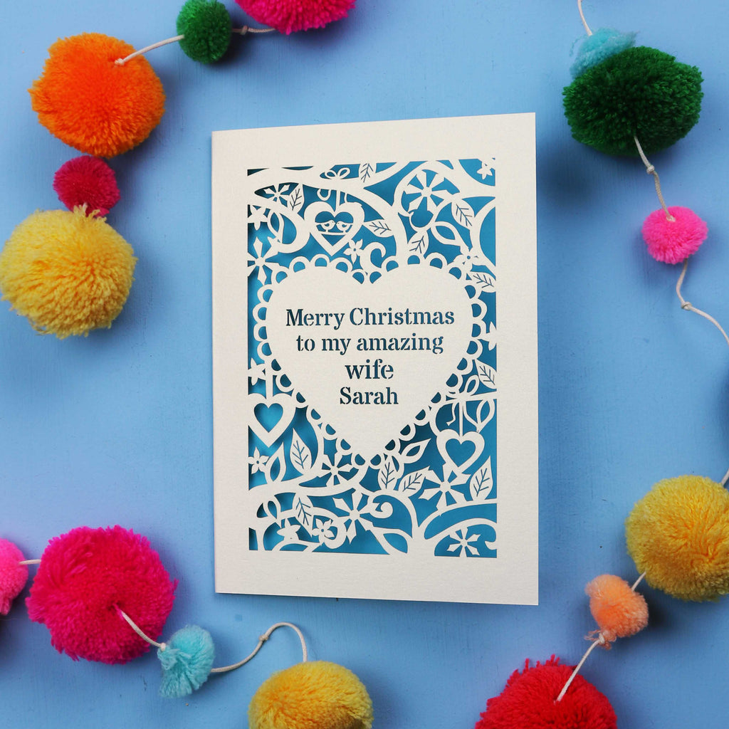 Wife Christmas card with personalized message on a blue background with colourful pom-poms.