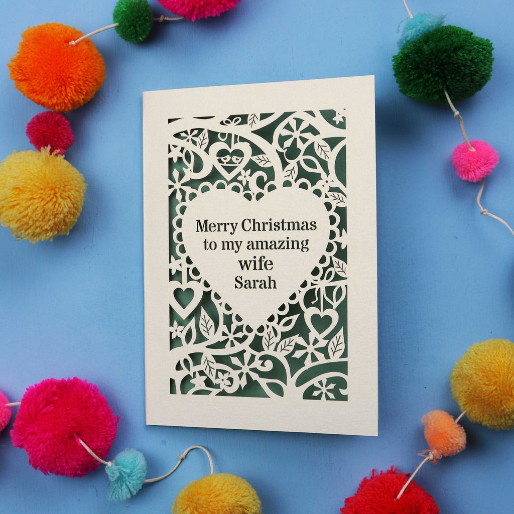 Christmas card with personalized message surrounded by colourful pom-poms on a blue background