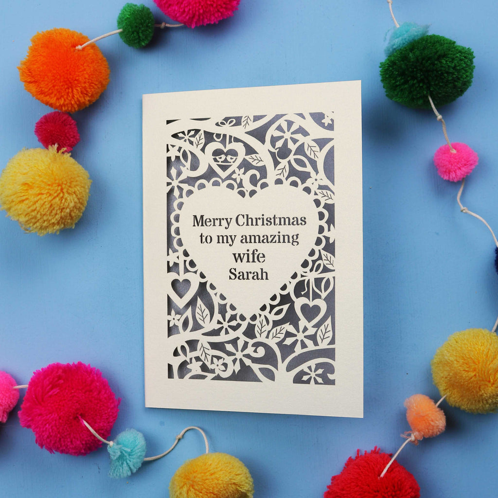 Wife Christmas card with personalized message on a blue background with colourful pom-poms.