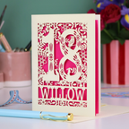 Decorative laser cut 18th birthday card with '18' and personalised with the name 'Willow', featuring floral designs and woodland creatures. Card stands on a desk with stationery items.