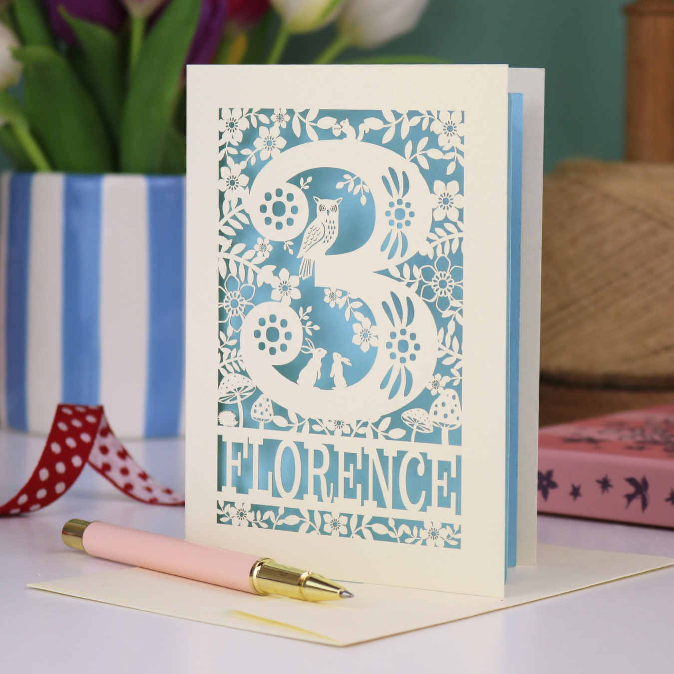 Decorative 3rd Birthday card with floral woodland and owl design, featuring the name 'Florence', on a table with a pen and flowers.