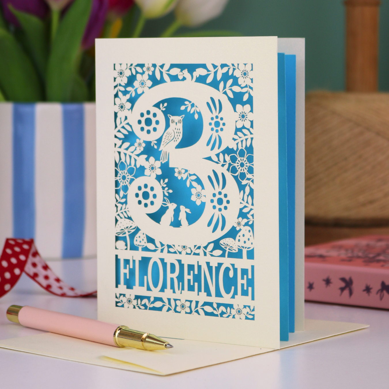 Decorative 3rd Birthday card with floral woodland and owl design, featuring the name 'Florence', on a table with a pen and flowers.