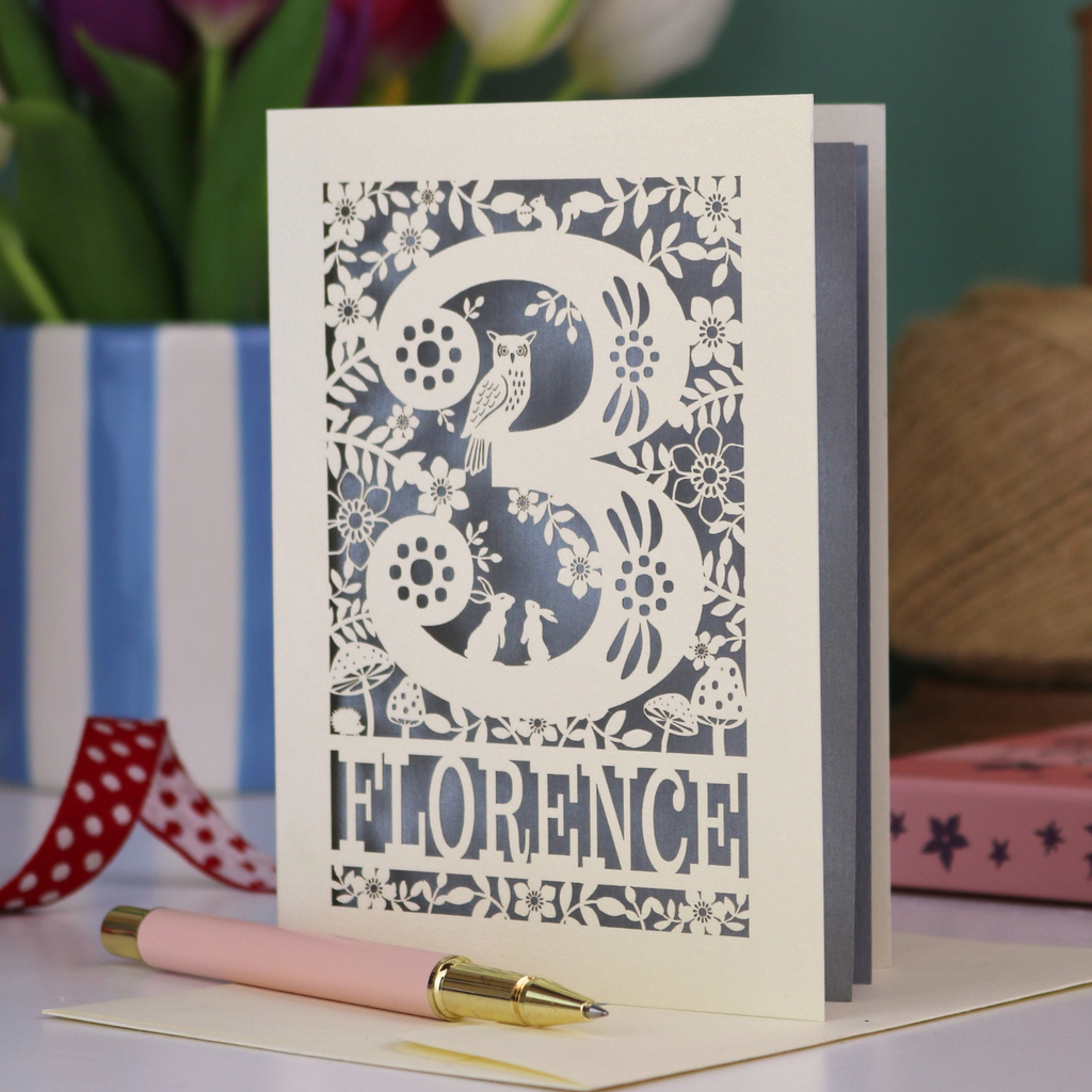Decorative 3rd Birthday card with floral woodland and owl design, featuring the name 'Florence', on a table with a pen and flowers.