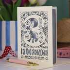 Decorative 3rd Birthday card with floral woodland and owl design, featuring the name 'Florence', on a table with a pen and flowers.