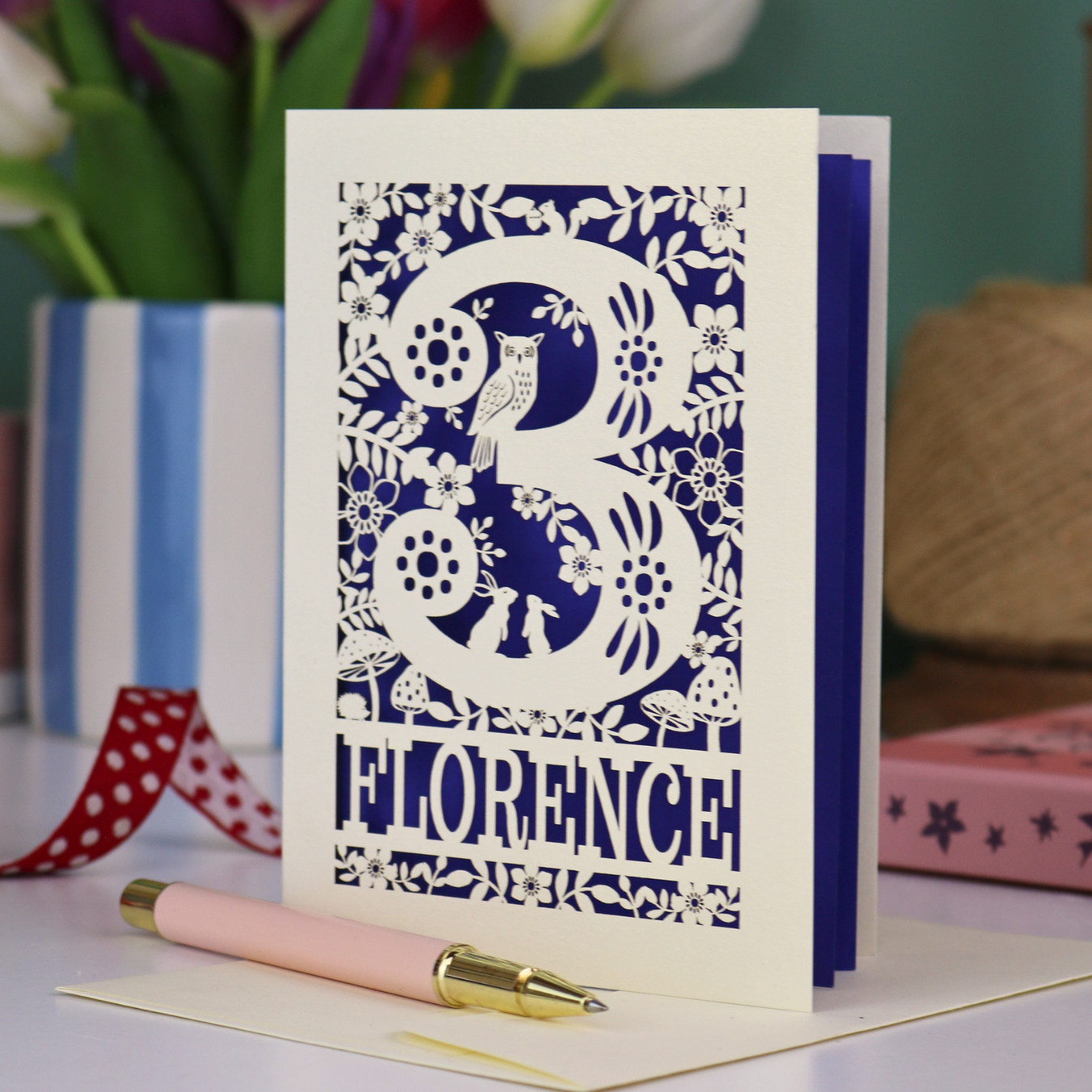 Decorative 3rd Birthday card with floral woodland and owl design, featuring the name 'Florence', on a table with a pen and flowers.