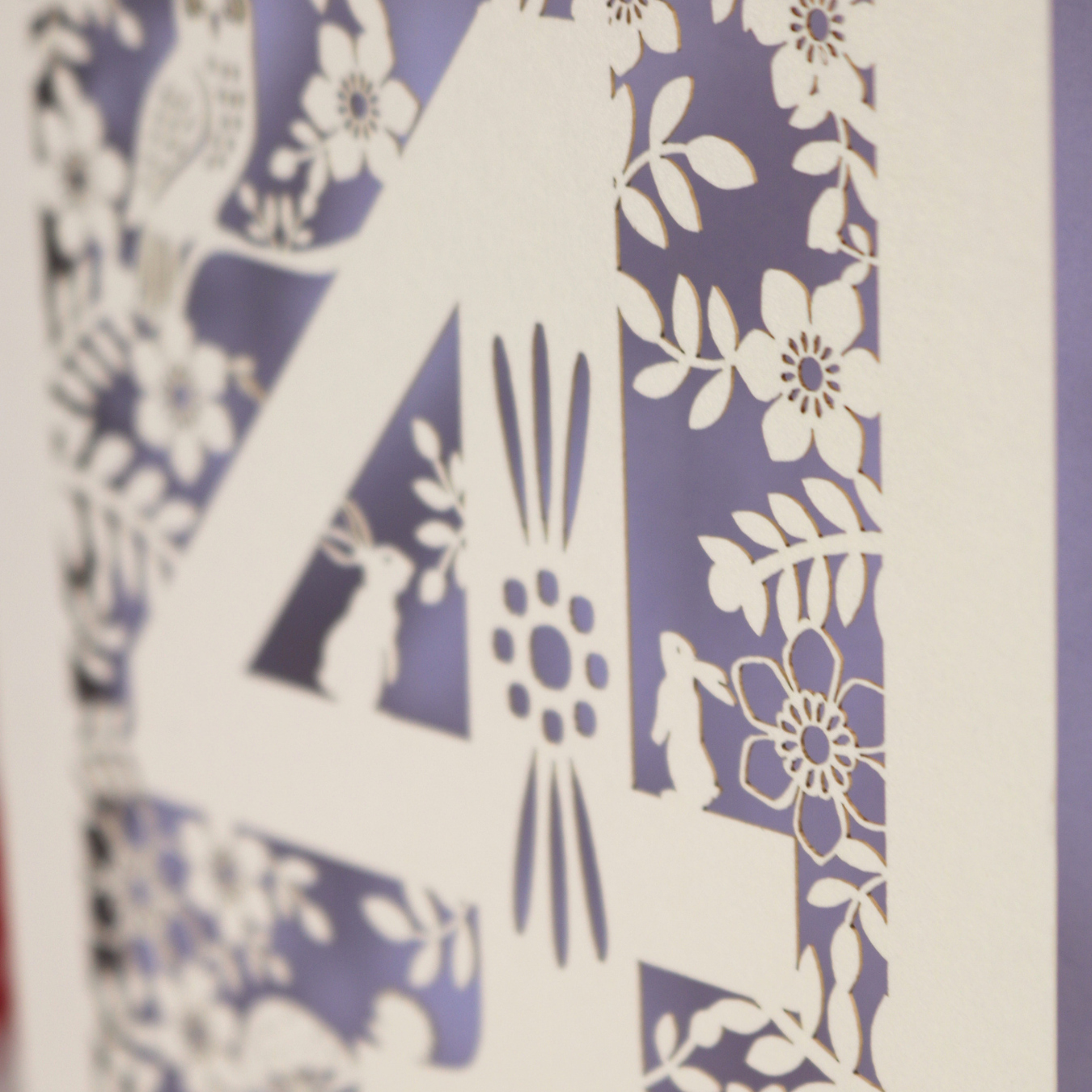 Decorative 4th Birthday card with woodland laser cut patterns, personalised with the name 'Harley', on a table with stationery items.