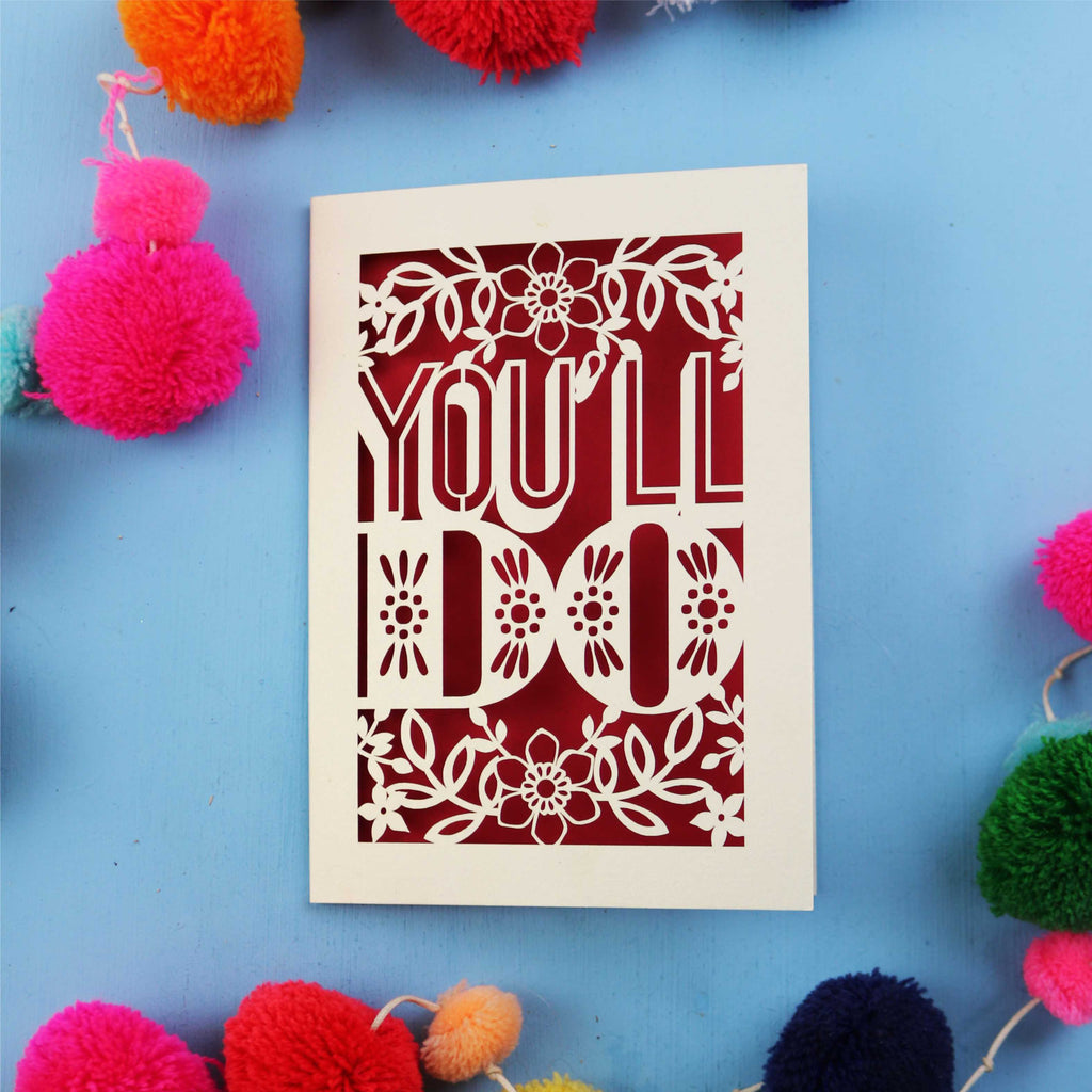  Laser cut  Valentine's card with 'YOU'LL DO' text on a blue background with colourful pom-poms.