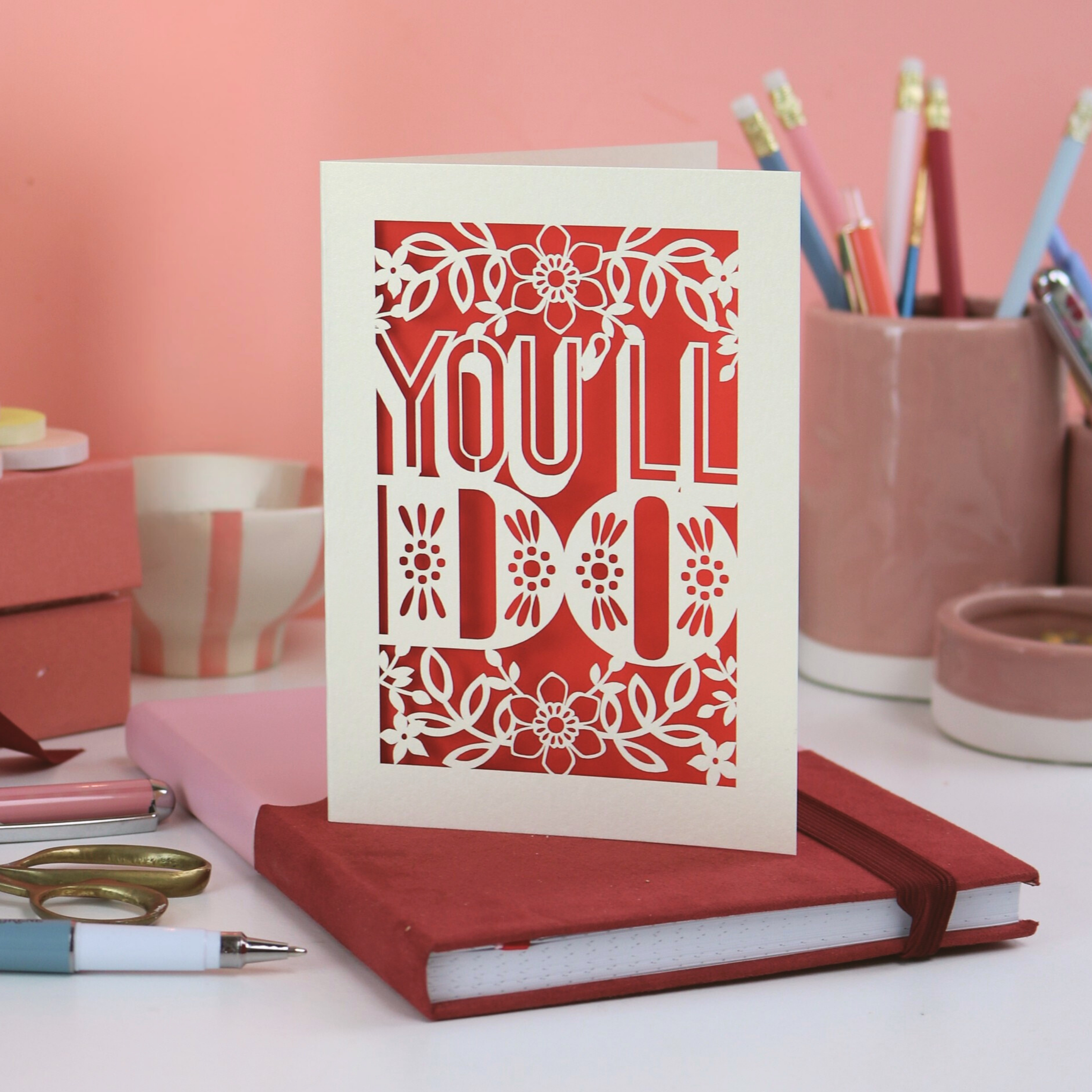 A laser cut funny Valentines card that says "You'll Do" on desk with pink background