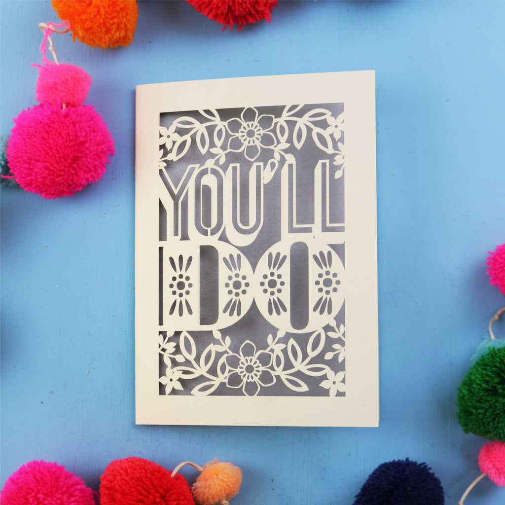 Decorative Valentine's card with 'YOU'LL DO' text on a blue background with colourful pom-poms.