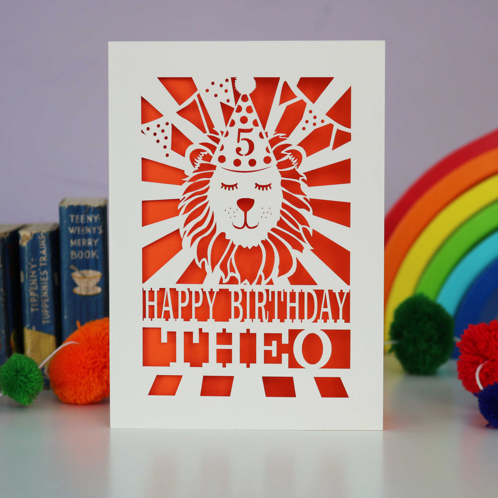 A laser cut lion birthday card, personalised with a name and age and featuring a lion in a party hat